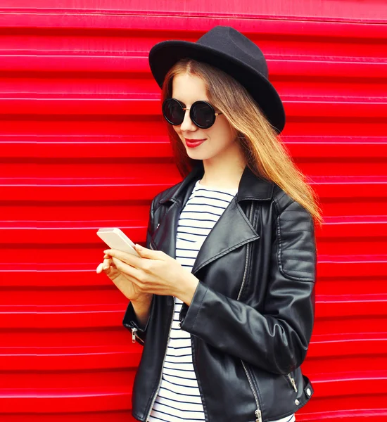 Jolie jeune femme utilisant un smartphone dans le style rock noir de mode — Photo