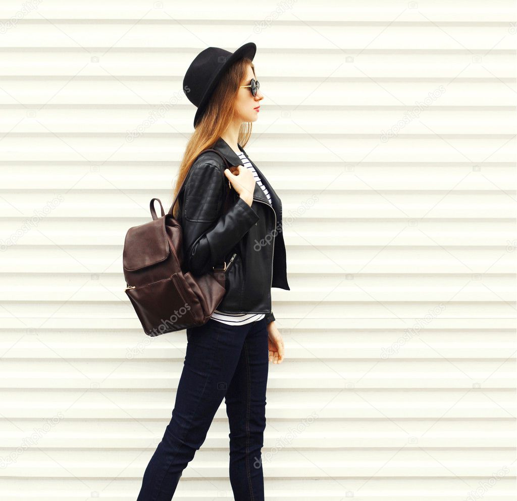 Fashion young woman in black rock style walking in city over emp