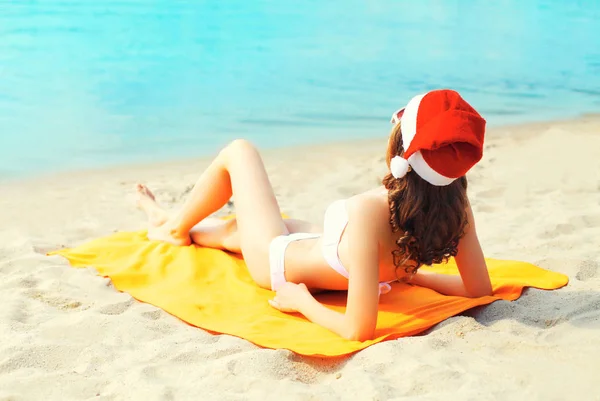 Boże Narodzenie młoda kobieta w czerwonym kapeluszu santa, relaks, leżące na piasku być — Zdjęcie stockowe