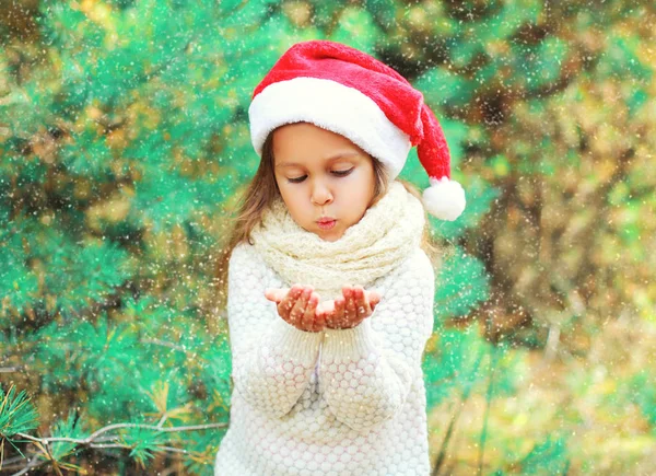 Enfant de Noël petite fille dans le chapeau rouge Père Noël soufflant la neige couché — Photo