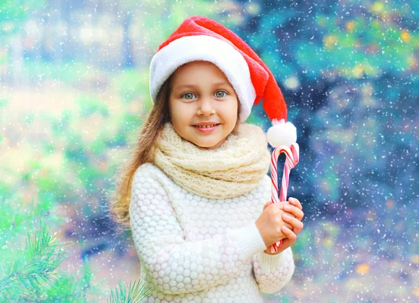 Christmas barn lilla flickan i röd Tomtemössa med söta lollipop — Stockfoto