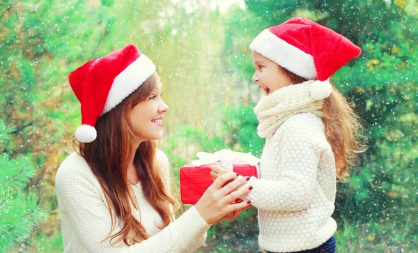 Vánoční dítě a matka v santa red hat s dárkové krabice — Stock fotografie