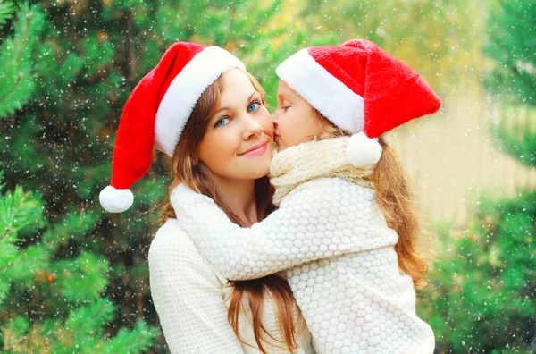 Christmas family child kissing mother in santa red hats together — Stock Photo, Image