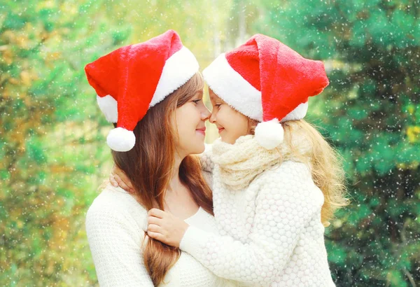 Natal criança da família abraçando a mãe em santa chapéus vermelhos juntos — Fotografia de Stock