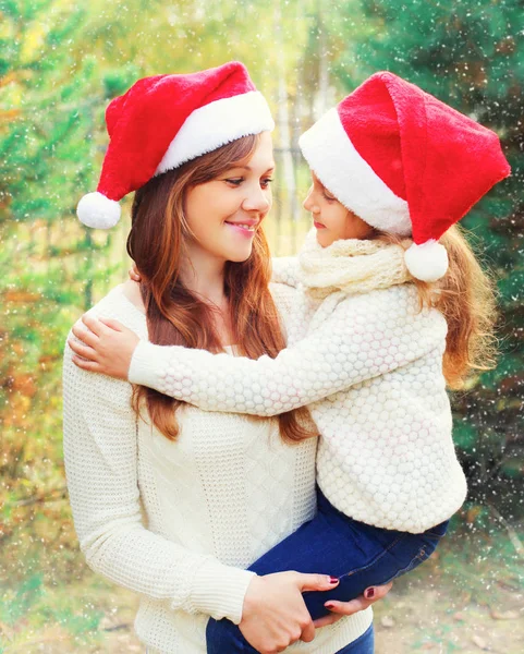 Natal família, criança abraçando a mãe em santa chapéus vermelhos juntos — Fotografia de Stock