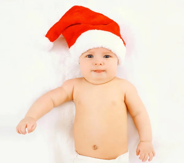 Christmas and family concept - cute baby in red santa hat lying Stock Image