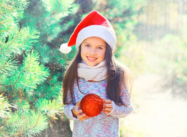 Christmas leende barn lilla flickan i röd Tomtemössa med bollen n — Stockfoto