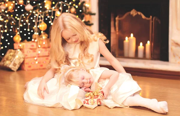 Criança menina dá uma caixa de presente para irmã sobre a árvore de natal — Fotografia de Stock