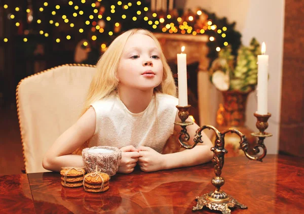 Criança de Natal soprando na vela faz um desejo sentado no ta — Fotografia de Stock