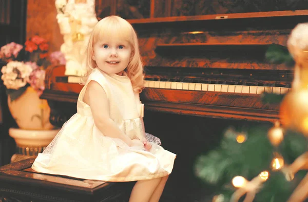 Natal sorrindo criança menina tocando piano em casa — Fotografia de Stock