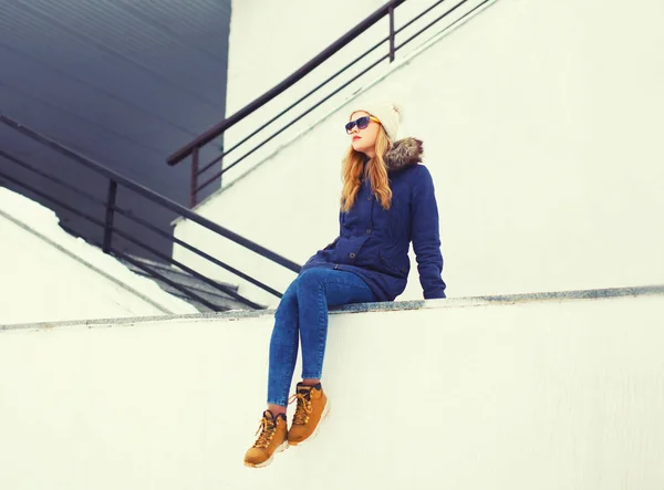 Fashion blonde woman sitting in winter city over white wall back — Stock Photo, Image