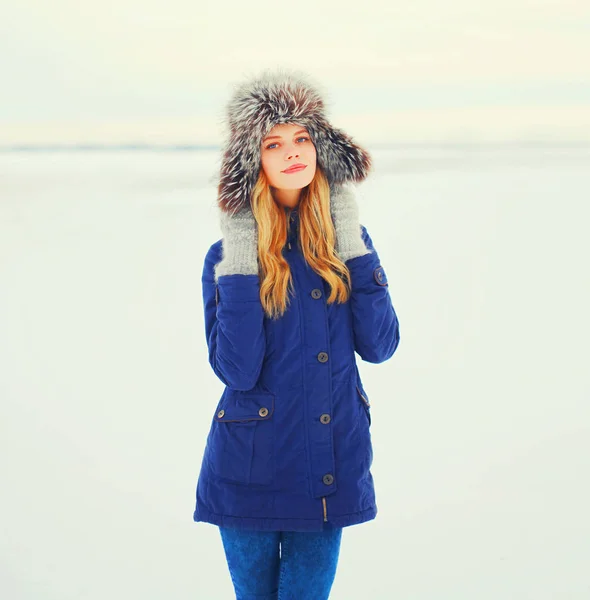 Winter fashion portrait smiling woman wearing a fur hat over sno — Stock Photo, Image