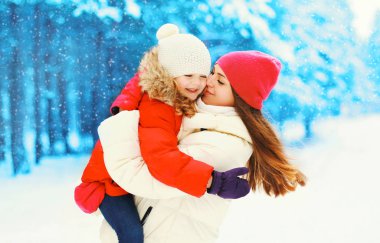 Kış mutlu gülümseyen anne sarılma öpüşme çocuk kar tanesi üzerinde