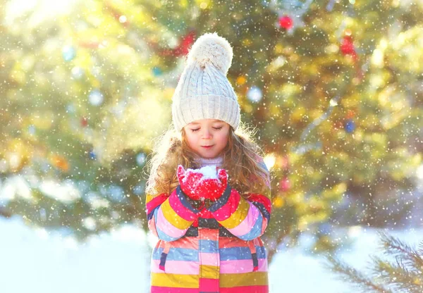 Зима счастливый маленький ребенок держит дует снег на ее руках — стоковое фото