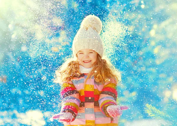 Vinter glada lilla barnet spelar kastar upp snö utomhus — Stockfoto