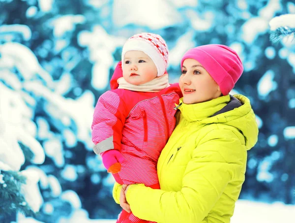 Winter portret gelukkige moeder houdt baby op handen boven besneeuwde chri — Stockfoto