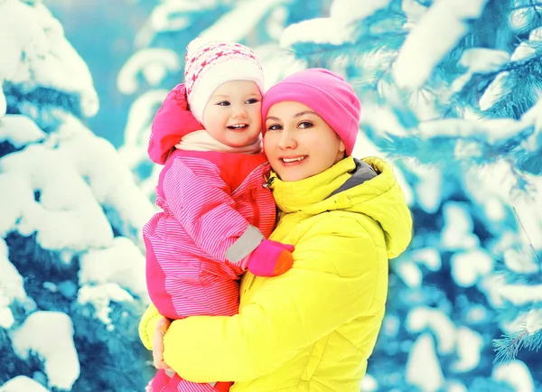 Vinter porträtt glada leende mor rymmer baby på händer över sn — Stockfoto