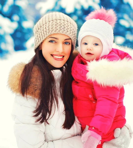 Portrait d'hiver heureux sourire mère et bébé sur les mains sur la neige — Photo