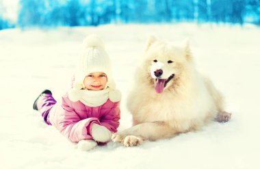 Mutlu gülümseyen çocuk ve yatan beyaz Samoyed köpek kış kar
