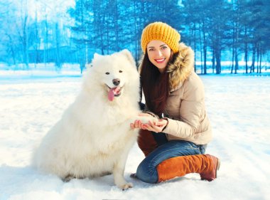 Beyaz Samoyed köpek üzerinde kış mutlu gülümseyen genç kadın sahibiyle