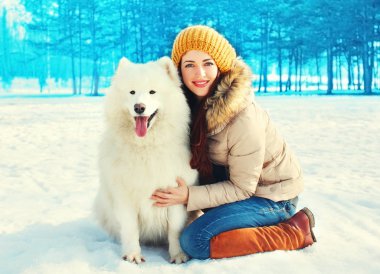 Kış genç gülümseyen kadın sahibi ile beyaz Samoyed köpek  