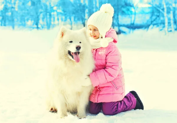 Criança feliz com cão Samoyed branco no inverno de neve — Fotografia de Stock