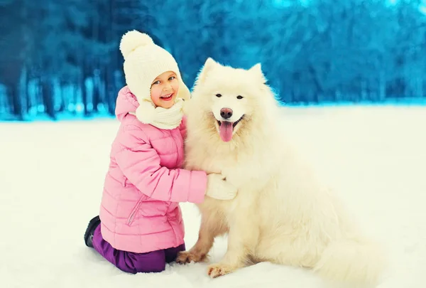 Happy smiling child playing with white Samoyed dog on snow winte — Stock Photo, Image