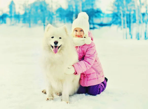 A téli hó fehér Szamojéd kutya boldog mosolygó gyermek — Stock Fotó