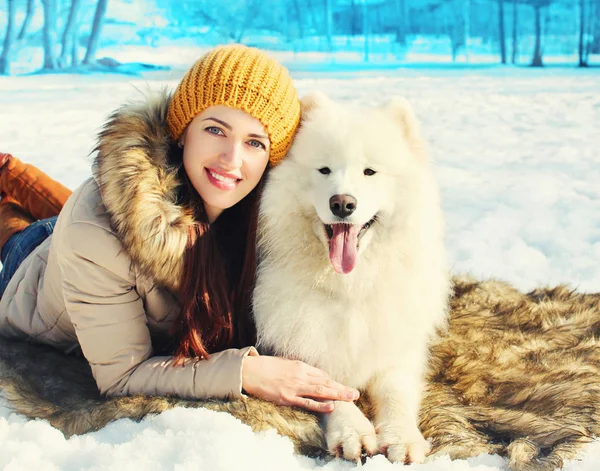 여자 소유자와 흰색 Samoyed 개 겨울 눈에 누워 웃 고 — 스톡 사진