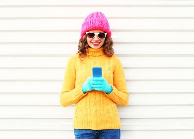 Moda güzel genç gülümseyen kadın Colo giyen smartphone kullanarak