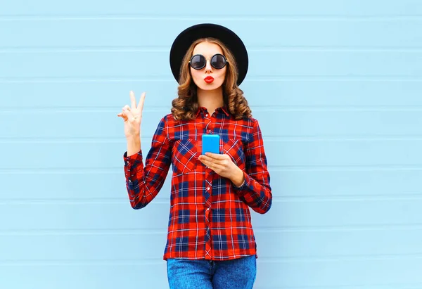 Moda bastante fresco joven mujer con teléfono inteligente soplado labios rojos — Foto de Stock