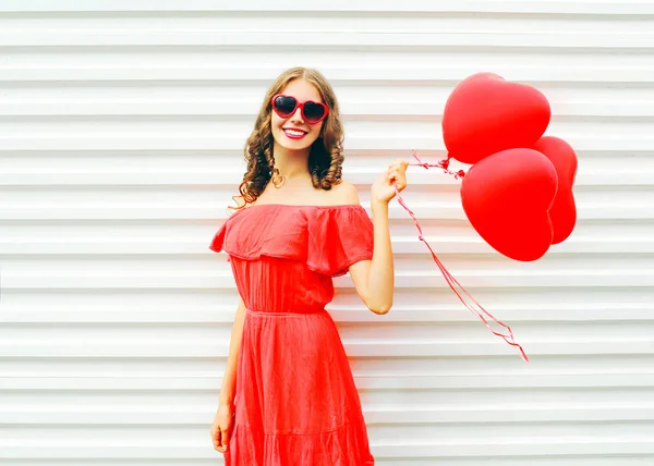 Ganska nöjd leende kvinna i röd klänning och solglasögon med luft — Stockfoto