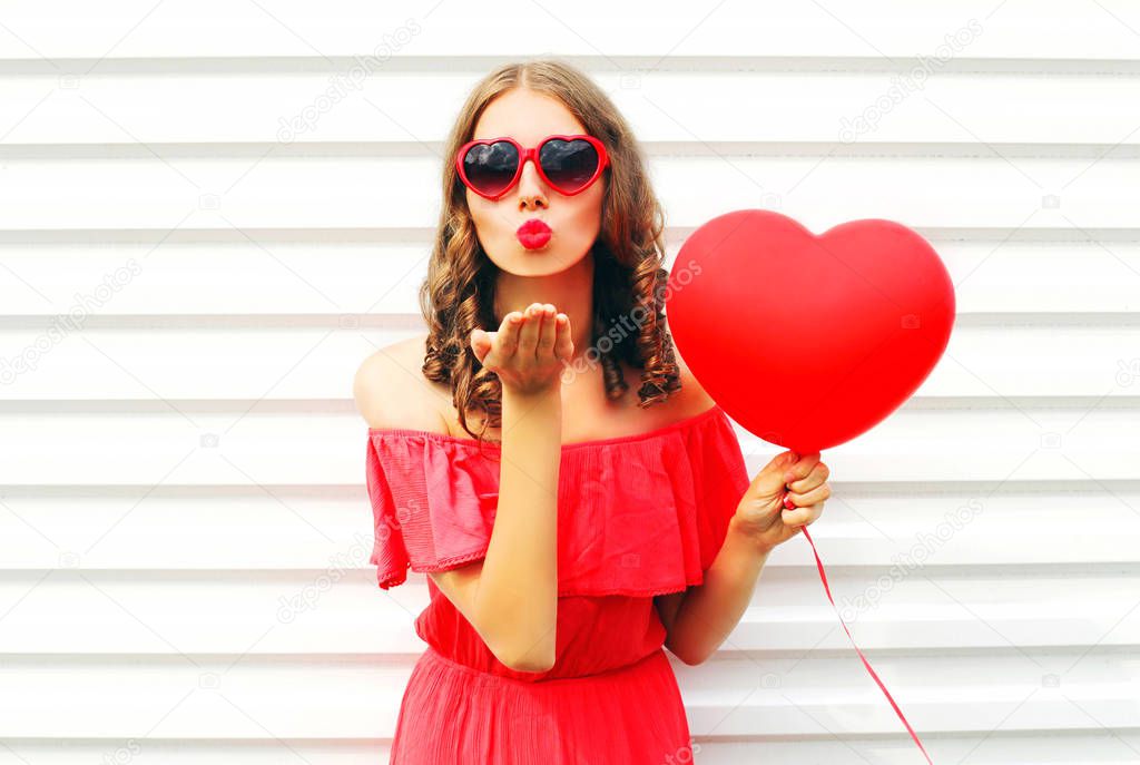 Portrait pretty woman in red dress sends air kiss with balloon h