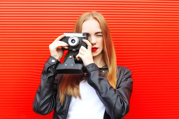 Divat csinos nő a város felett piros háttérben vintage kamerával — Stock Fotó