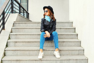 Siyah kaya ceket şapka sitti giyen genç ve güzel kadın moda