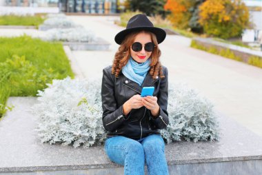 Siyah kaya ceket smartphone kullanarak genç kadın moda, 