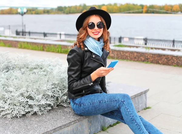Мода молода усміхнена жінка використовує смартфон у чорному камені — стокове фото