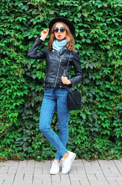 Mujer joven de moda con chaqueta de roca negra, sombrero y bolso encima — Foto de Stock