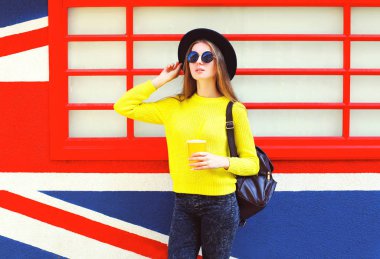 Kupası renkli kentsel arka plan üzerinde tutan moda güzel kadın