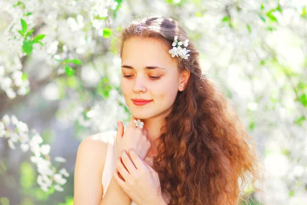 Portrait beautiful young woman over flowering spring garden back — Stock Photo, Image