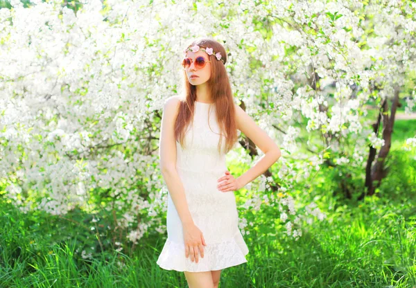 Fashion beautiful woman over flowering garden background on gras