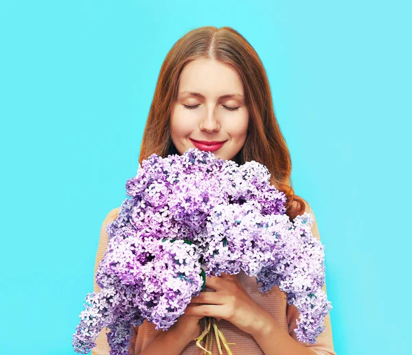 Feliz mujer sonriente disfrutando del olor de ramo flores lila clos — Foto de Stock