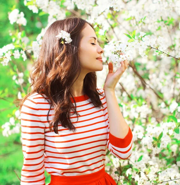 Hermosa mujer joven disfrutando del olor flores de primavera en el jardín — Foto de Stock