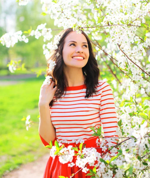 Gelukkig lachende jonge vrouw over lente bloemen achtergrond — Stockfoto