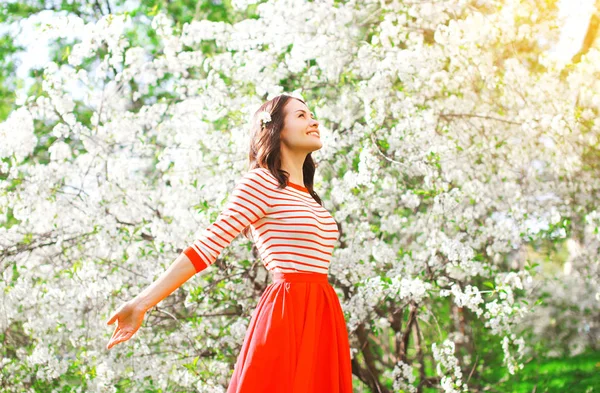 Mujer feliz disfrutando del olor flores sobre fondo de jardín de primavera — Foto de Stock
