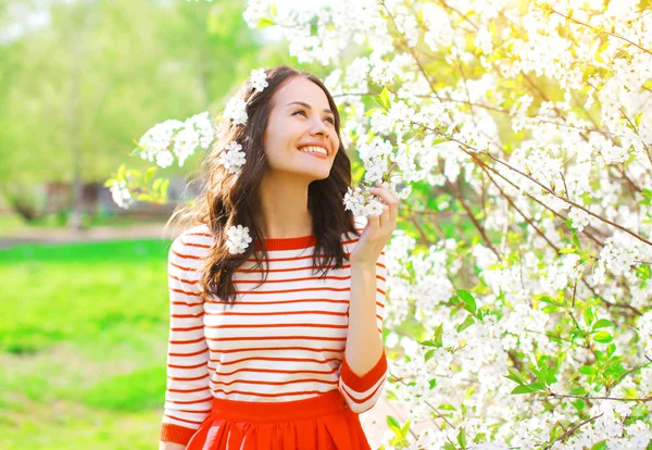 Happy smiling young woman with spring flowers at garden — Stock Photo, Image