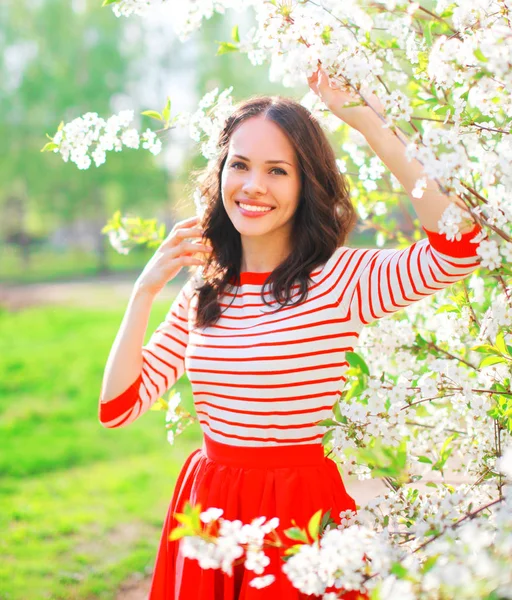 Portrait happy smiling young woman with spring flowers at garden — Stock Photo, Image