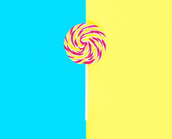 Colorful lollipop caramel on stick over blue yellow background t