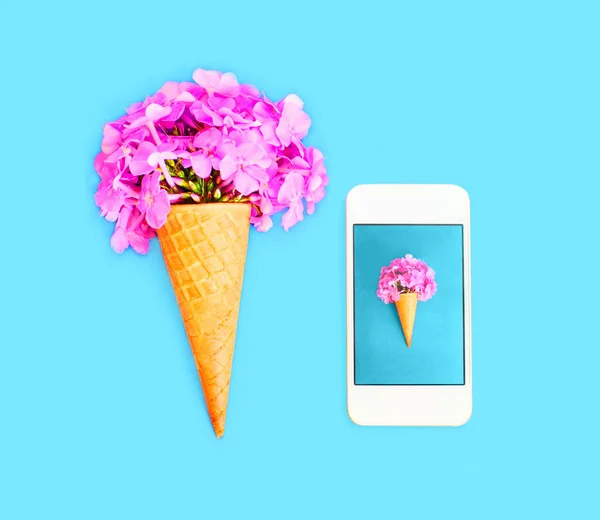 Cono de helado con flores y teléfono inteligente sobre ba colorido azul —  Fotos de Stock
