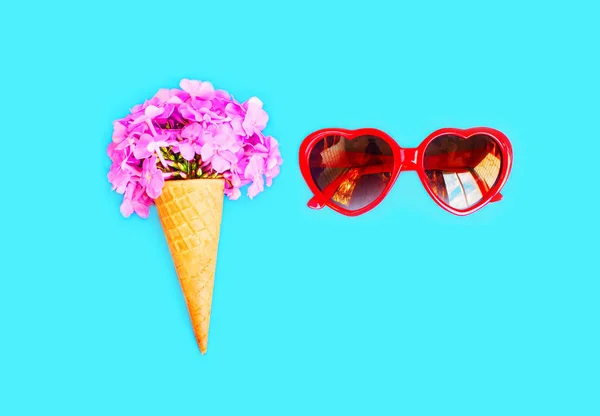 Cône de crème glacée avec des fleurs et des lunettes de soleil rouges forme de coeur sur — Photo